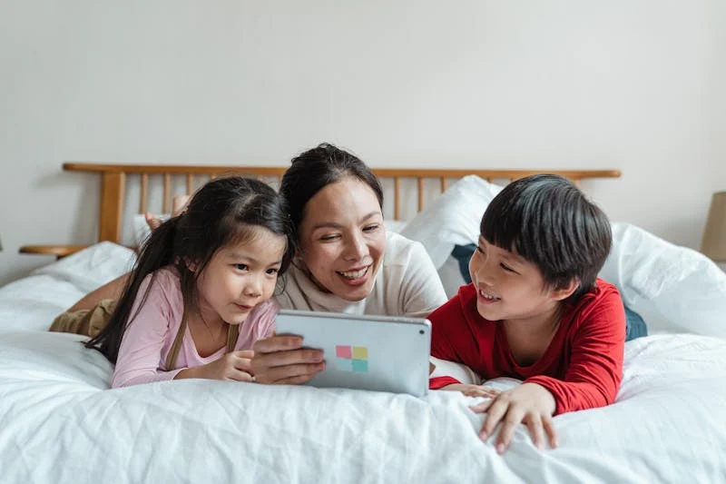 "Mother watching a tablet with her two children, illustrating balanced screen time and family bonding."

